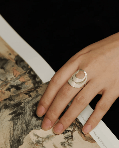 silver filigree ring on hand over Chinese ink painting – heritage jewelry style