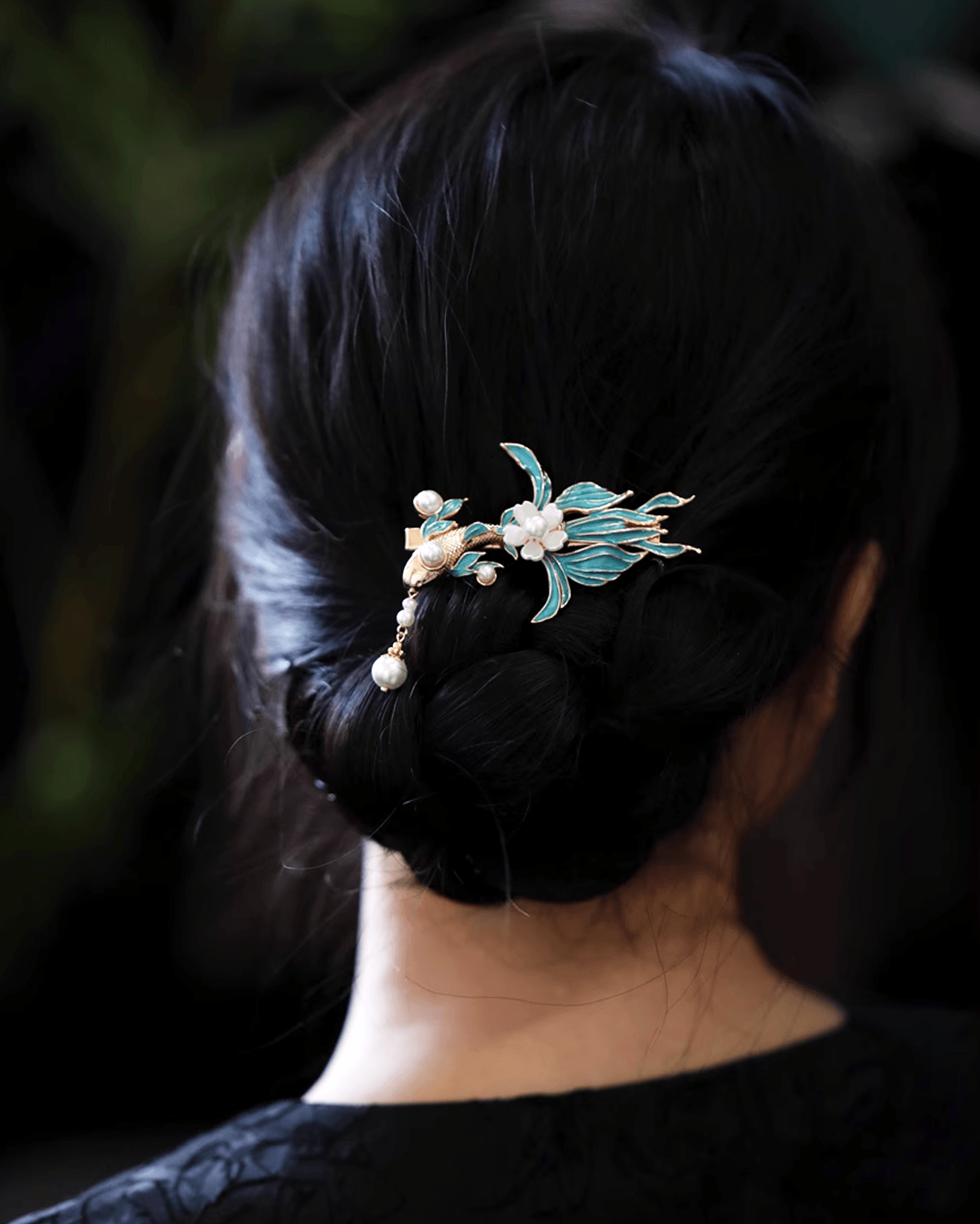 Side view of blue koi hair clip styled in a minimalist low bun, adding symbolic charm to modern look