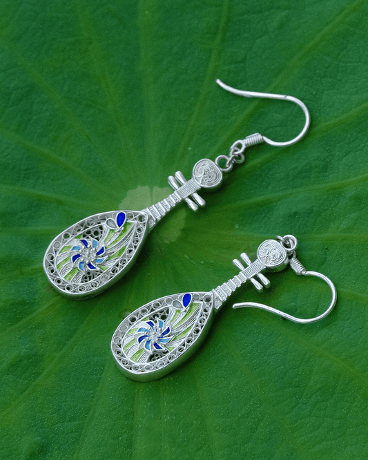 Close-up of handmade silver pipa earrings with lotus and enamel details — symbolic Oriental jewelry rooted in traditional Chinese craftsmanship.