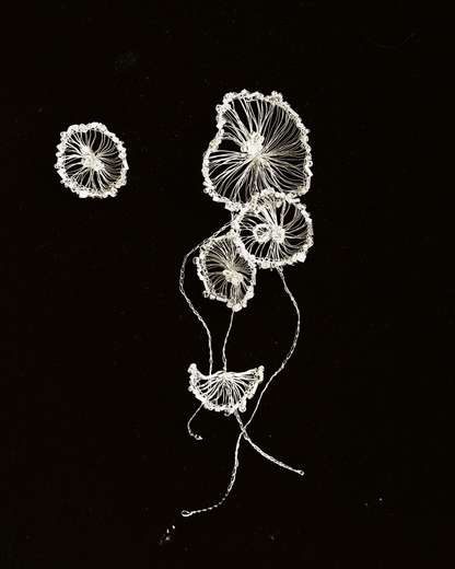 Close-up of silver-plated crocheted wire forming fluid, tentacle-like shapes on long dangle earrings