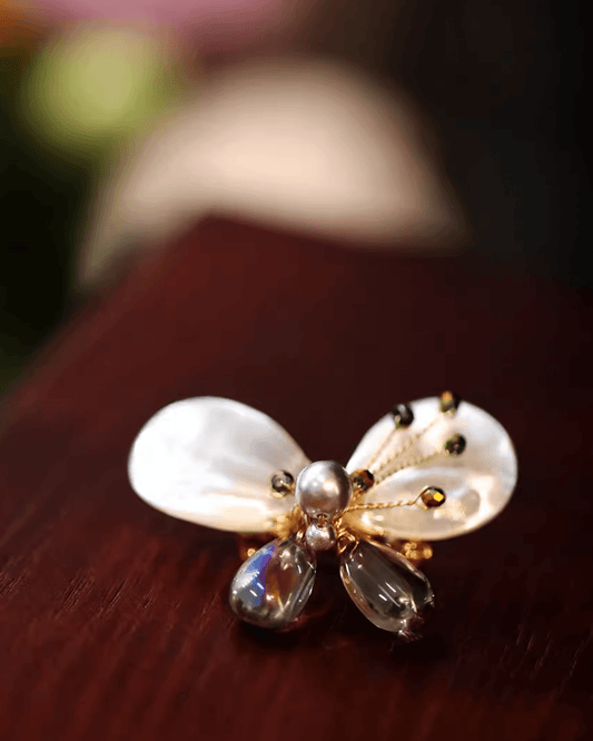 Close-up of antique-style metal antennae and iridescent abalone wings, showcasing craftsmanship and texture