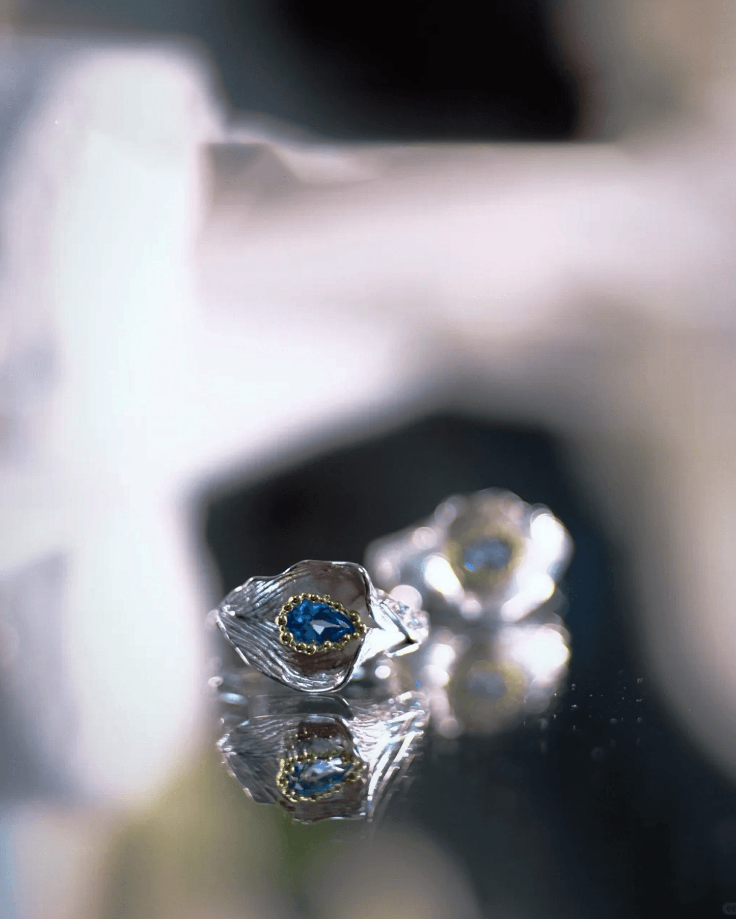 Close-up of blue topaz gemstone reflecting moonlit lake hues, embraced by two calla lily petals