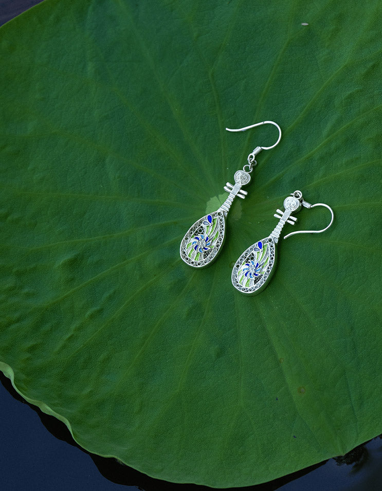 Sterling silver filigree earrings with cloisonné enamel resting on, handcrafted Chinese cultural jewelry inspired by Dunhuang.