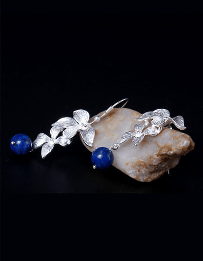 Flat lay of zolanjewelry Lapis Lazuli Dangle Earrings, celestial orchid earrings featuring hand-cut 6mm natural lapis lazuli stones with golden pyrite flecks, set in sterling silver filigree petals